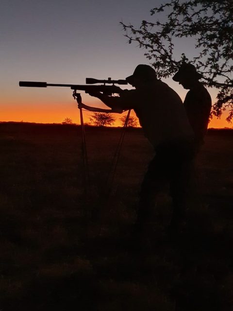 Jäger mit Gewehr auf einem Zielstock im Sonnenuntergang